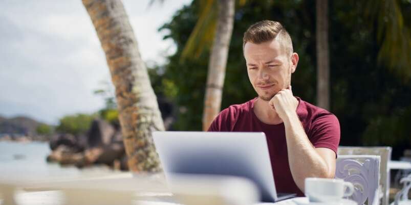 Man working on laptop on beach