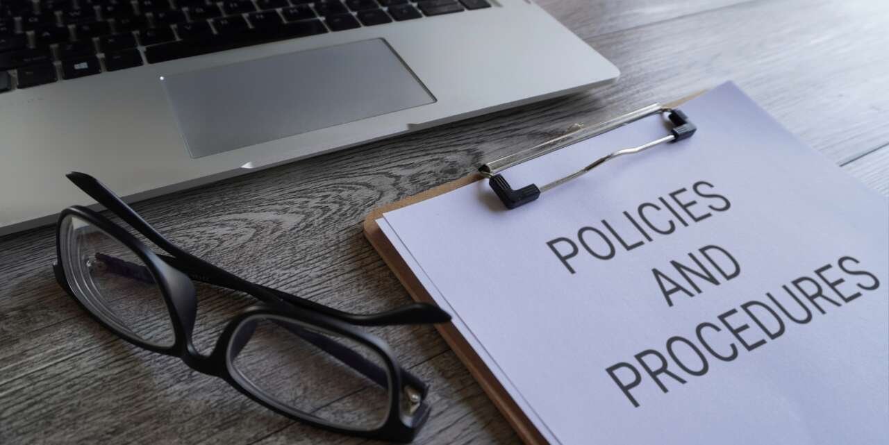 Paper clipboard with text POLICIES AND PROCEDURES on table