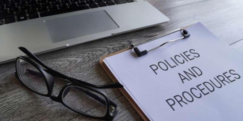 Paper clipboard with text POLICIES AND PROCEDURES on table