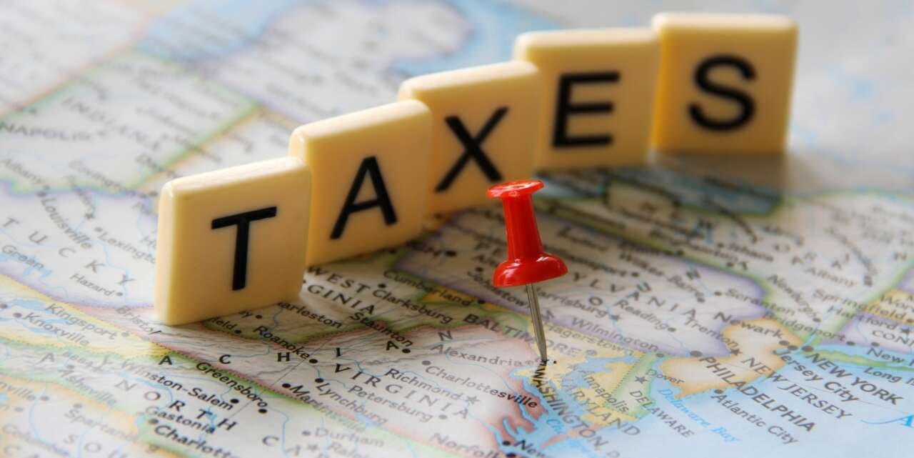 Red push pin marking Washington DC in map word taxes in letter tiles for tax filing season