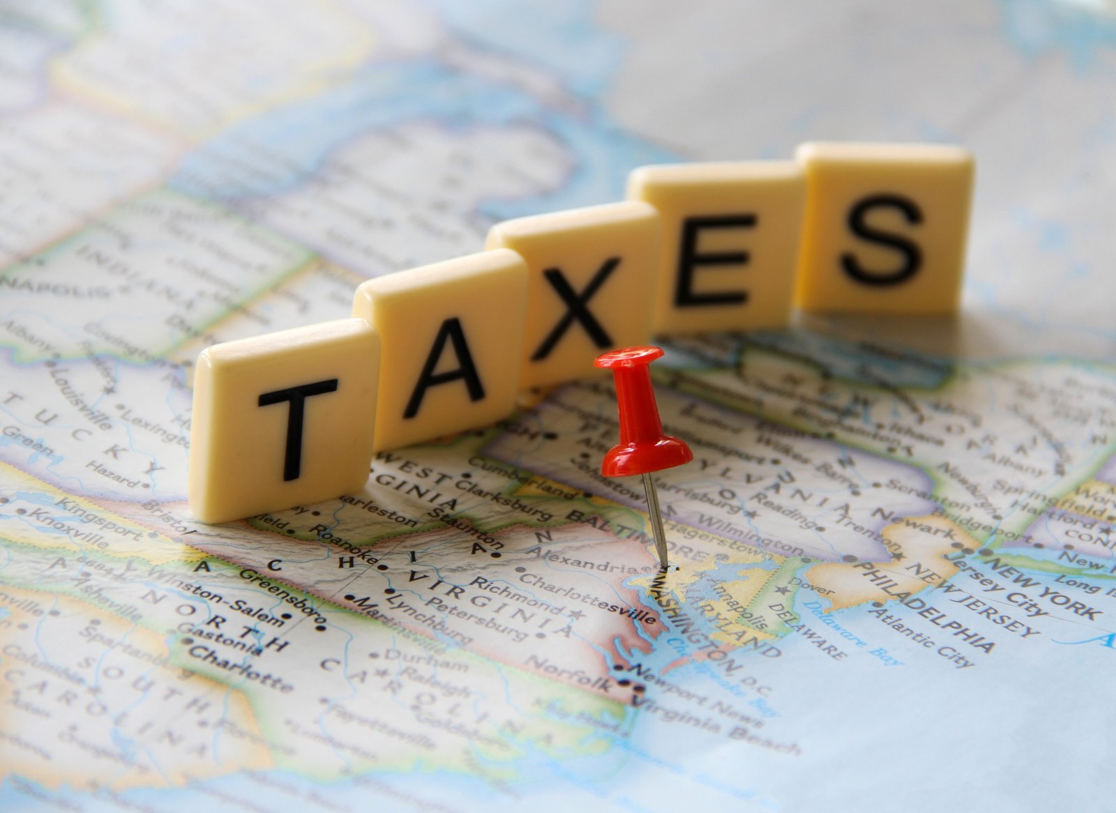 Red push pin marking Washington DC in map word taxes in letter tiles for tax filing season