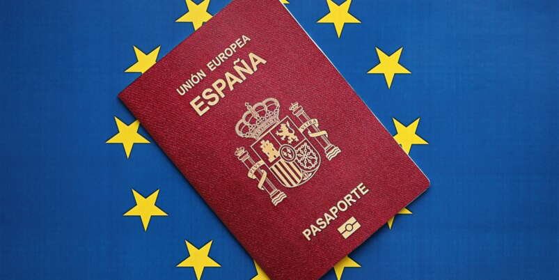 Red Spanish passport of European Union on blue flag background close up