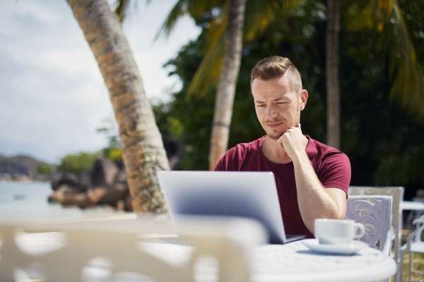 Man working on laptop on beach