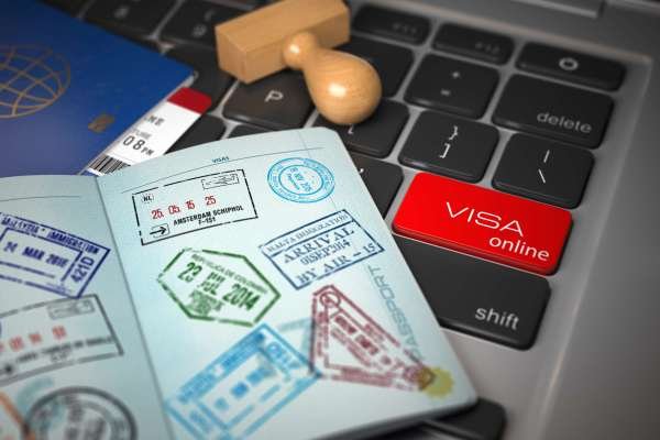 Visa online application concept. Open passport with visa stamps with airline boarding pass tickets and stamper on the computer keyboard. 3d illustration